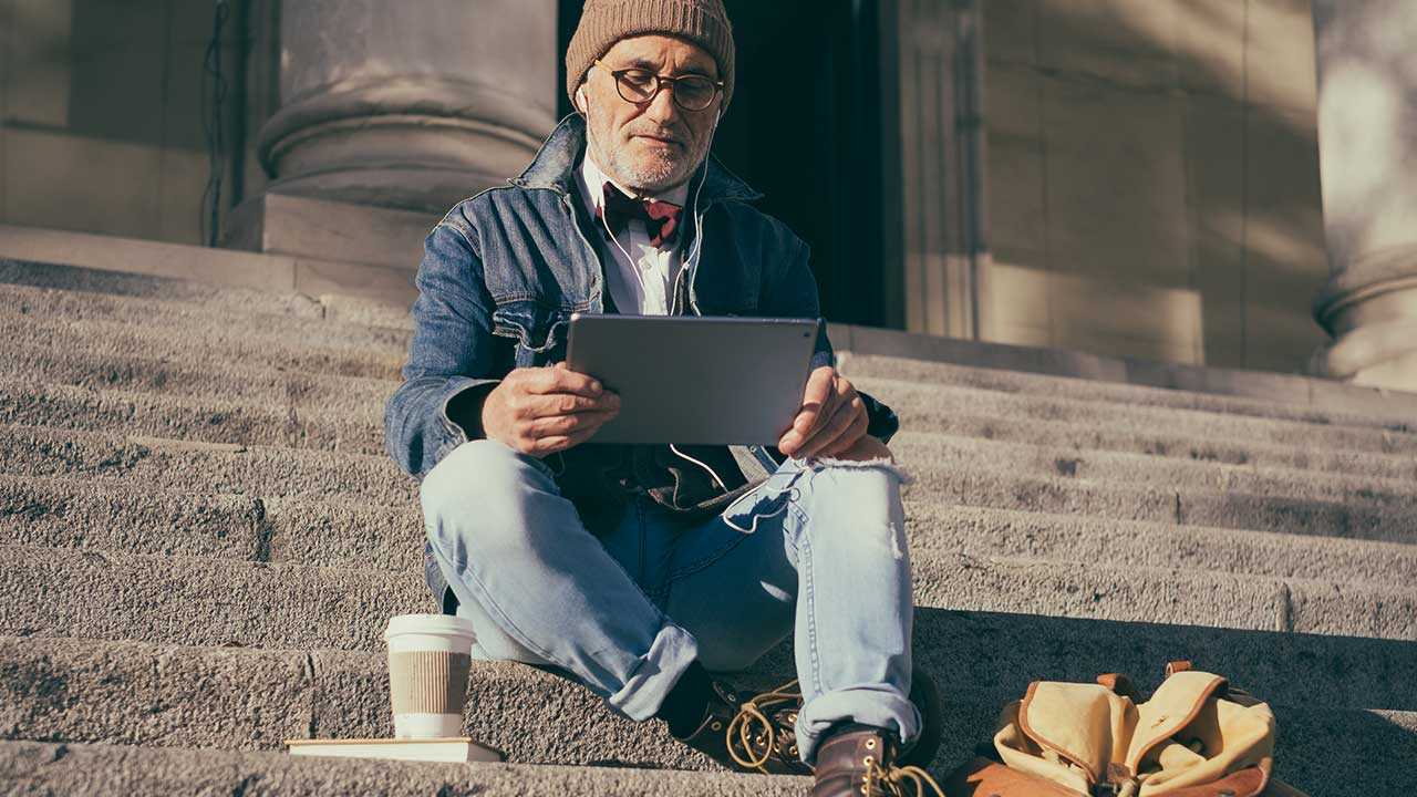 Unternehmer sitzt mit Tablet auf Stufen und liest