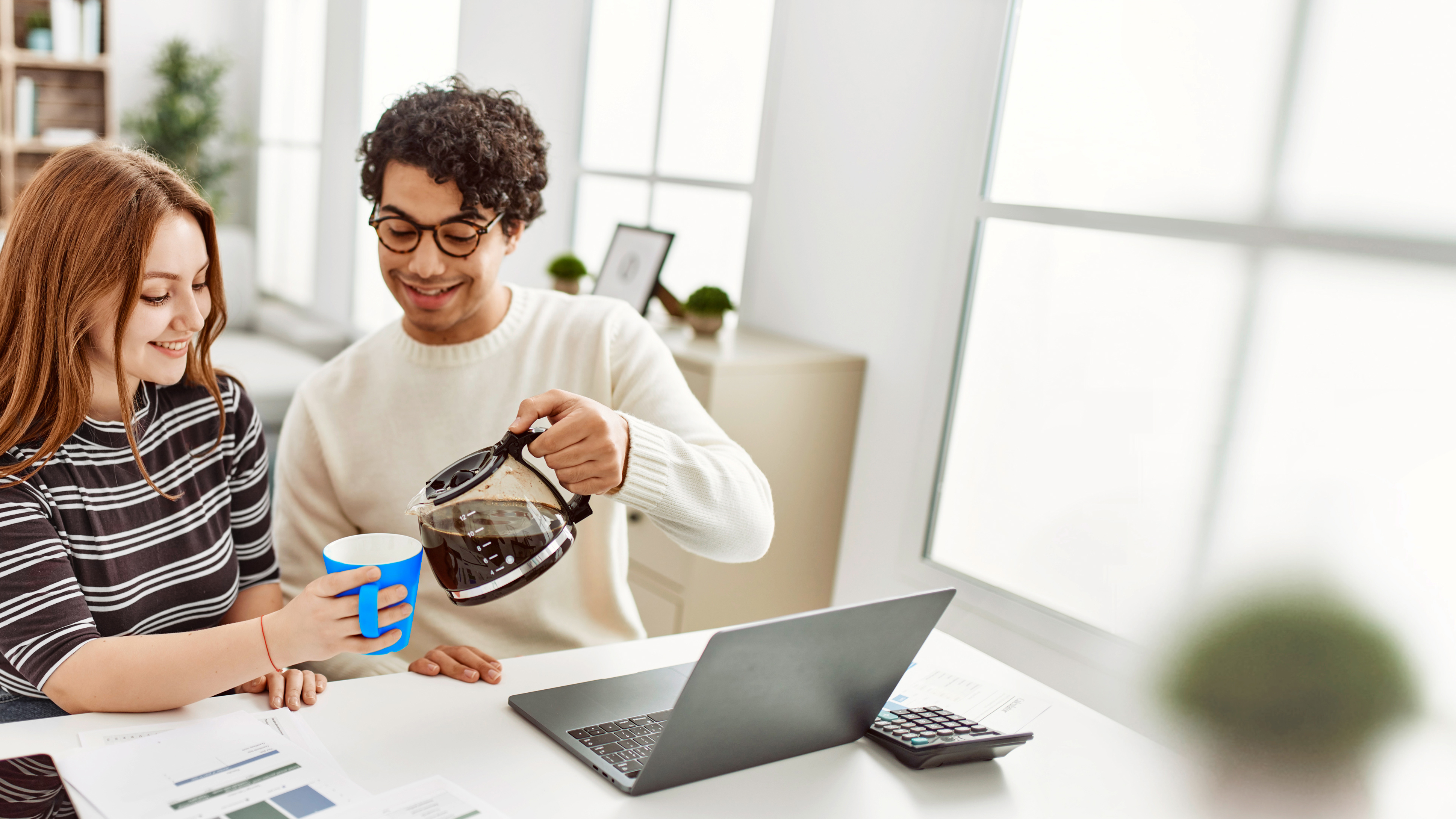 Frau und Mann mit Kaffee vor Laptop