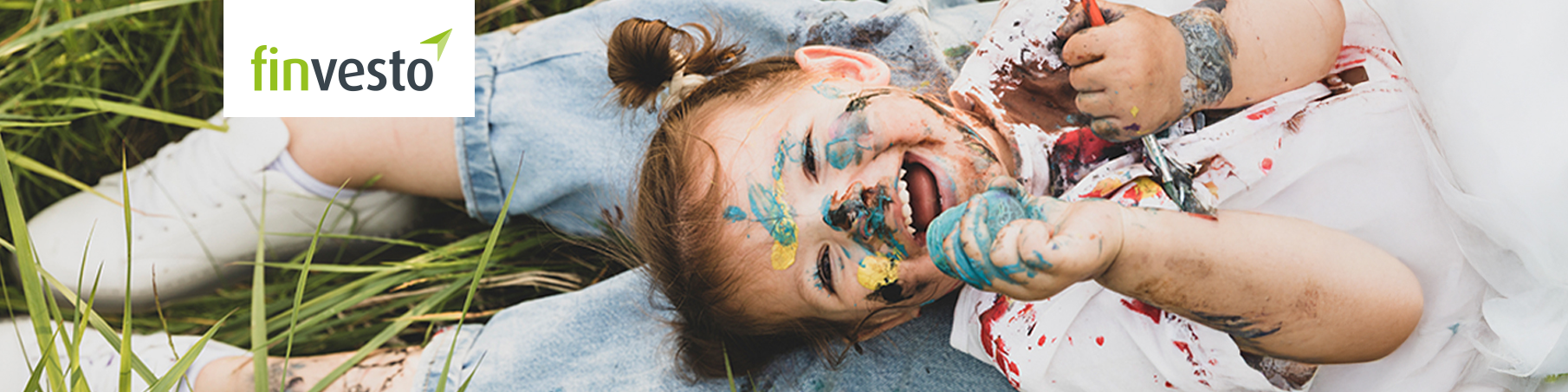 Lachendes Kind mit Farbe im Gesicht liegt auf Schoß